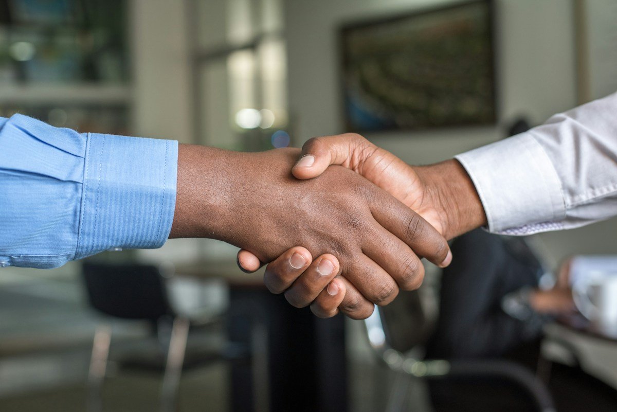 Two people meeting and shaking hands across an office desk