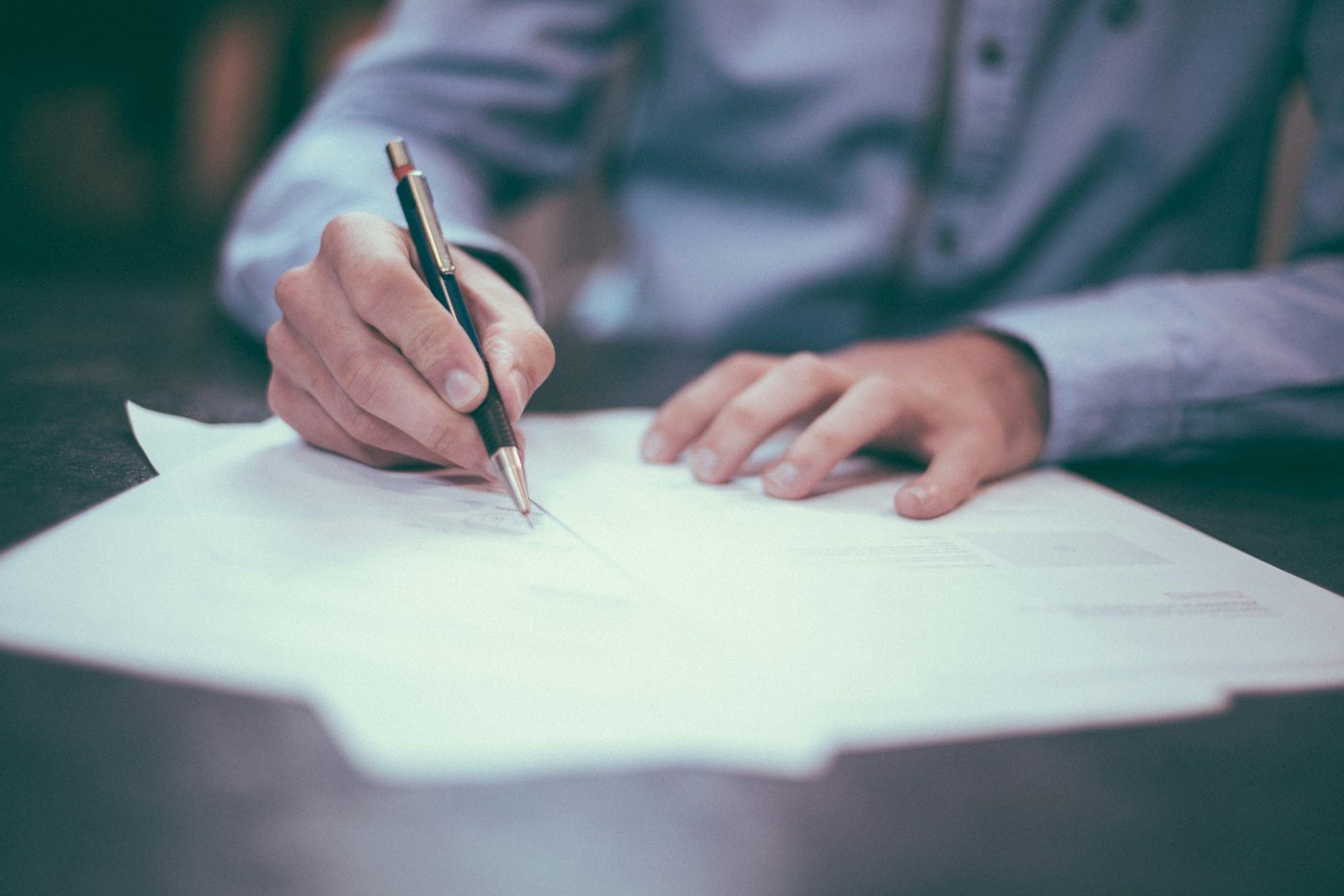 A professional reviewing and signing documents at a desk
